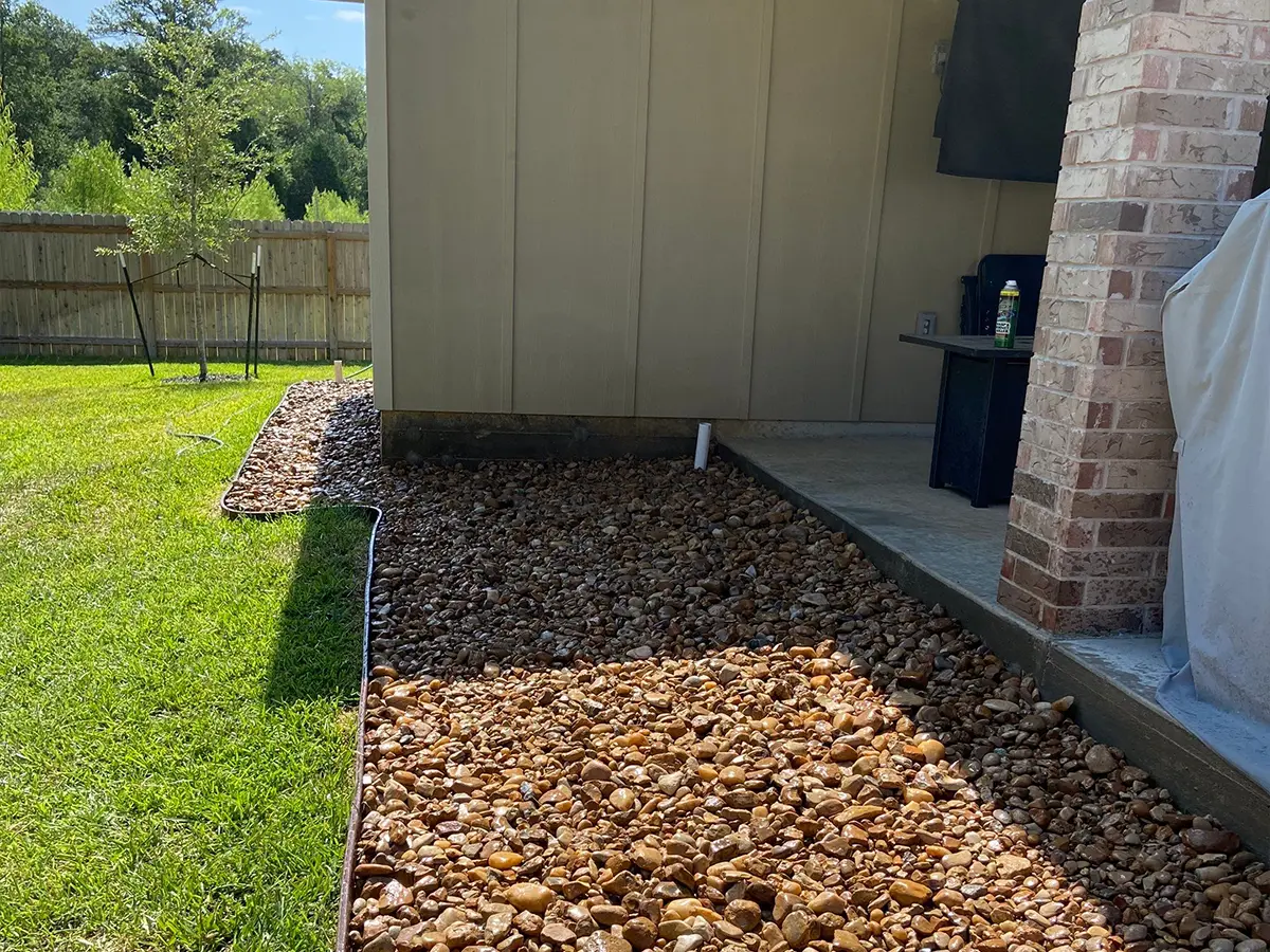Pebbles and rocks as part of a xeriscaping project in a backyard with a lawn