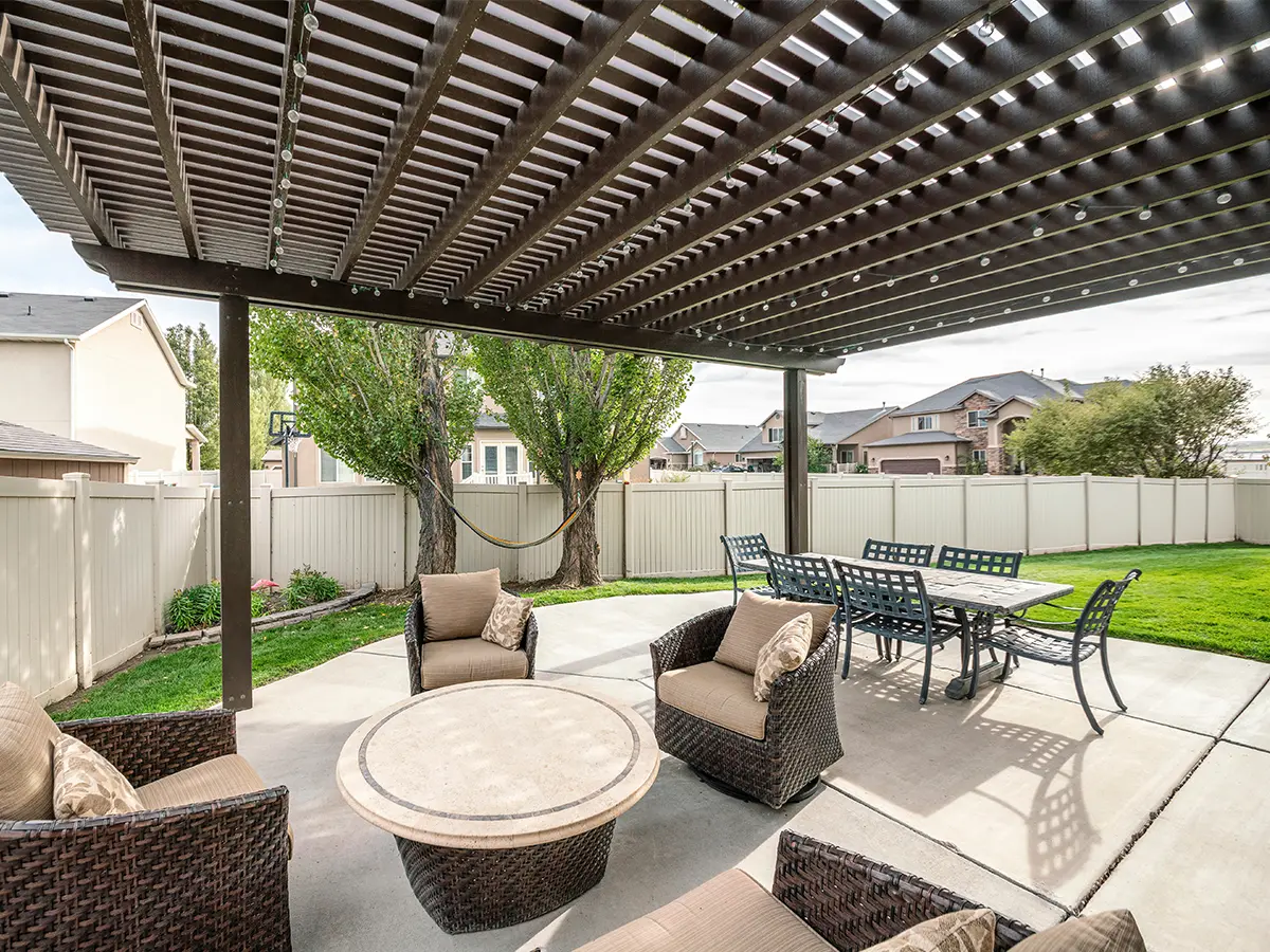 A concrete patio with a pergola and outdoor furniture