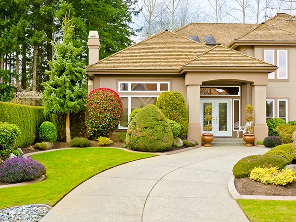 A walk-way made with concrete slabs and a beautiful landscape in the front yard