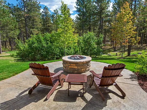 A patio with two chairs, a small table, and a round firepit