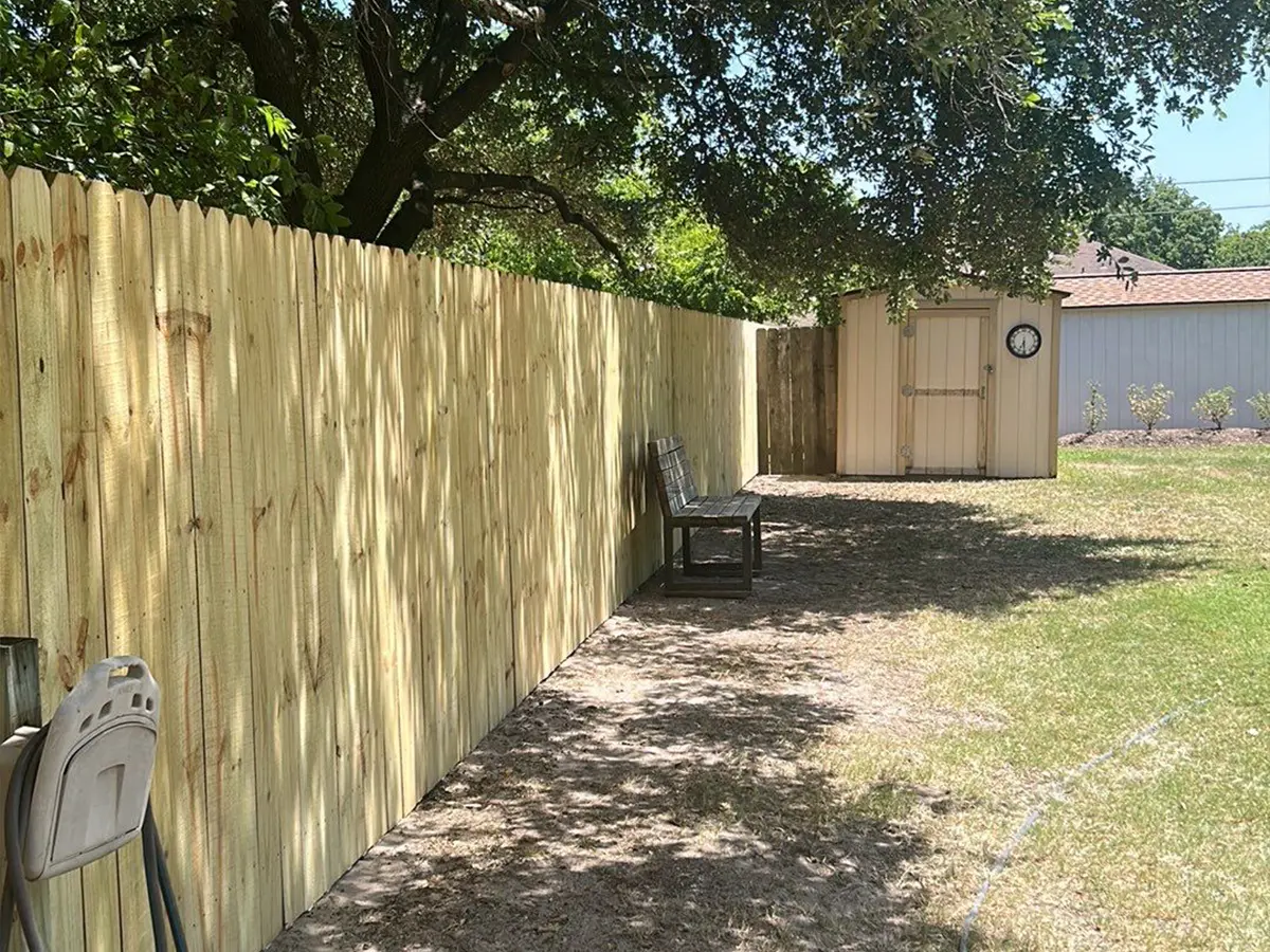 A pressure-treated fence and a small shed