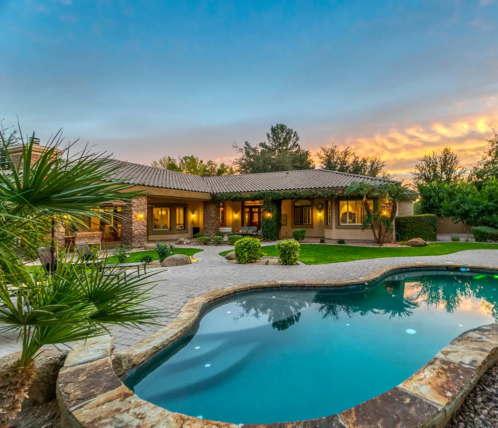 A large pool with a walkway and a patio made of pavers