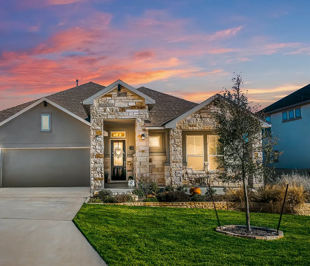 A front yard landscaping project with a concrete driveway and a veneer stone siding for a home in Brazos County, TX