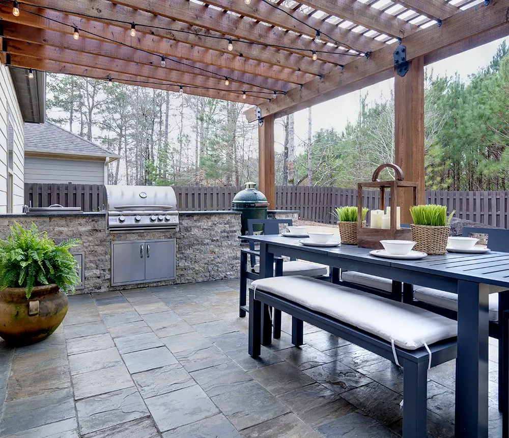 An outdoor kitchen with a stamped concrete patio and aluminum outdoor furniture