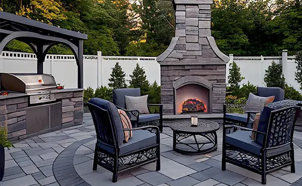 A large patio with outdoor furniture, an outdoor kitchen, and a tall fireplace