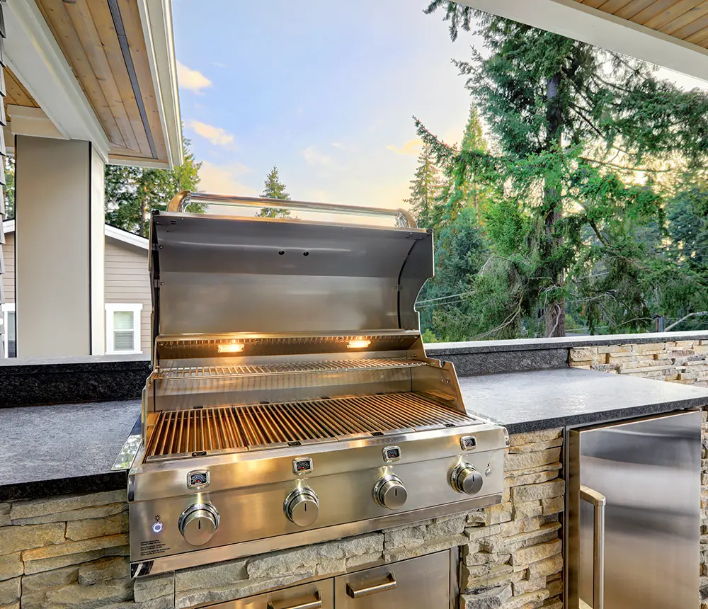 A grill on a black countertop in an outdoor kitchen