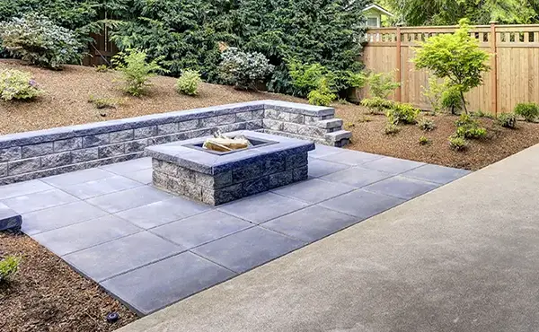 A patio made of concrete slabs and a square firepit