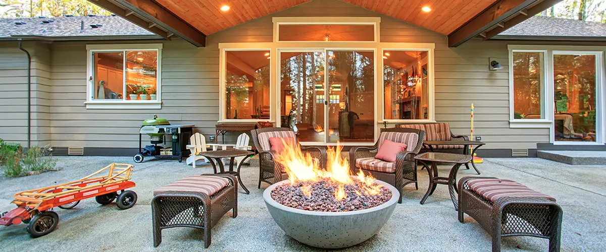 Cozy backyard patio with modern fire pit, wicker furniture, and a wood-paneled ceiling, perfect for an outdoor living space in Beverly Estates.