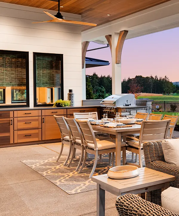 Luxurious outdoor patio with cozy seating, dining area, and sunset view over a landscaped garden