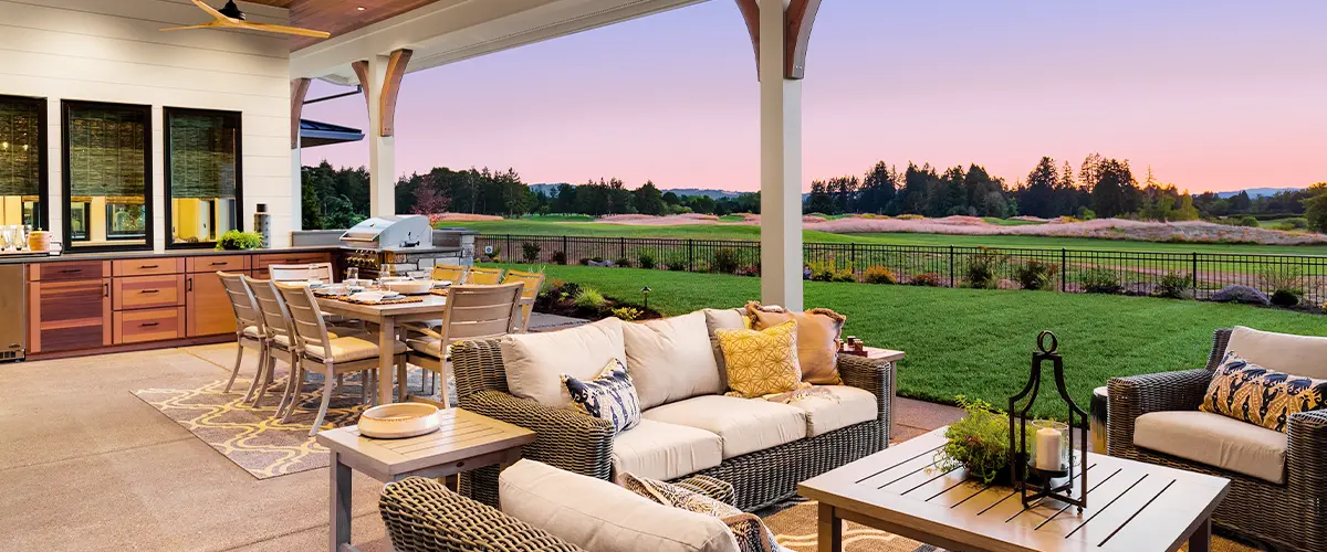 Luxurious outdoor patio with cozy seating, dining area, and sunset view over a landscaped garden