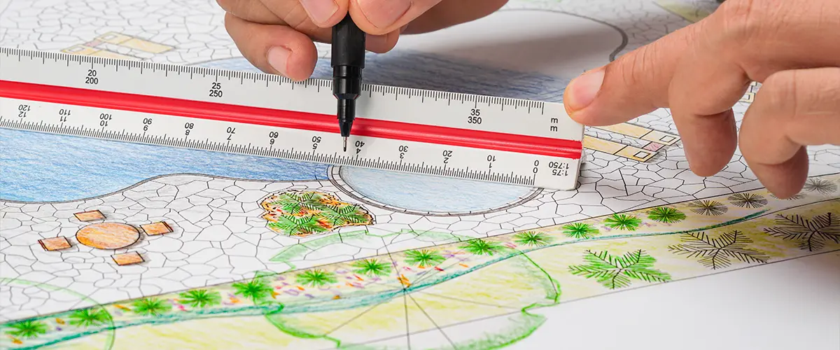 Architect drawing a detailed landscape design plan with ruler and marker—professional garden and outdoor space planning.