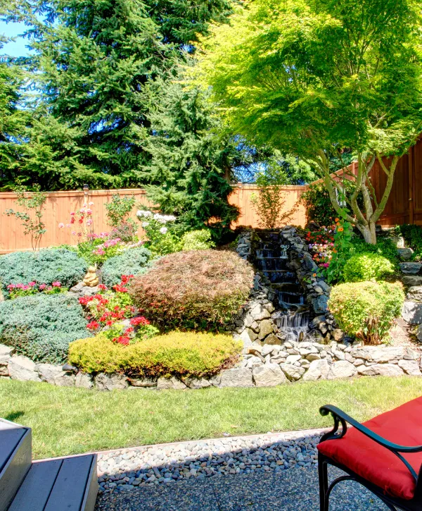 A peaceful Japanese rock garden featuring bonsai trees, decorative stones, and greenery.