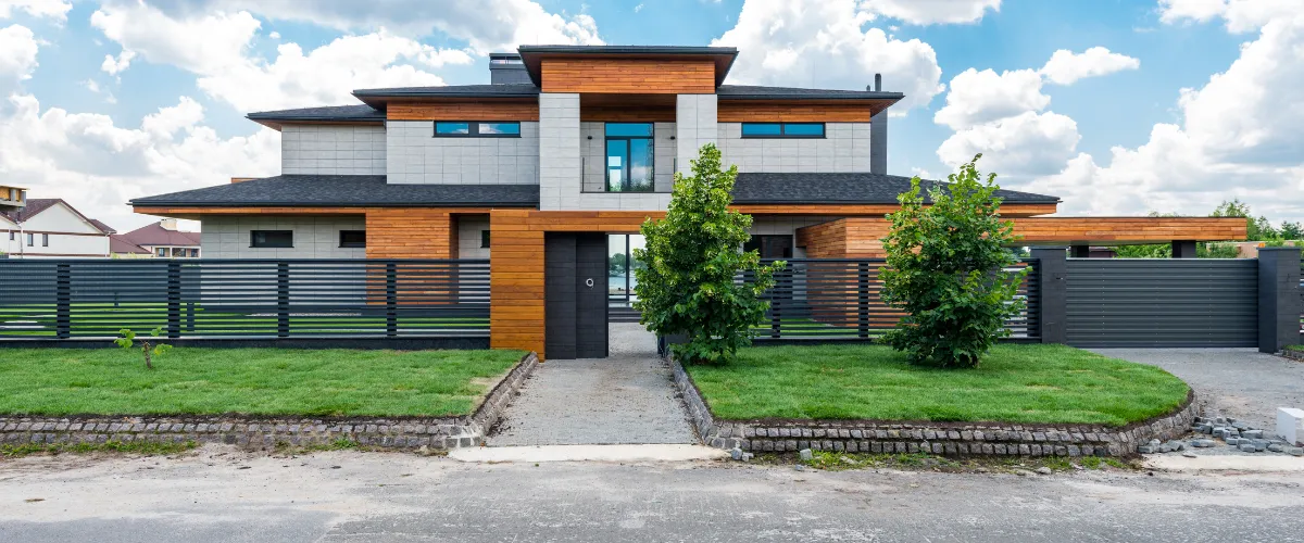 A luxury home with an expansive green lawn, elegant landscaping, and modern architecture.