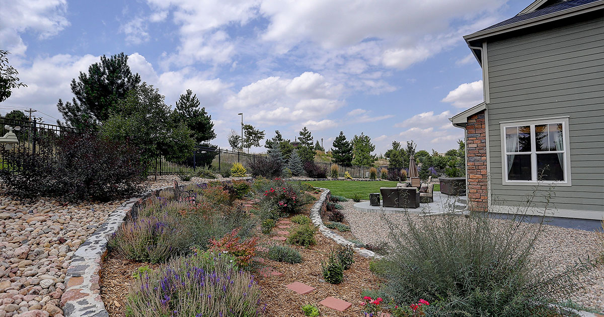 Drought-Resistant Landscaping Ideas for Bryan, TX Homeowners with native plants, mulch, stone edging, and a curved path beside a suburban home.