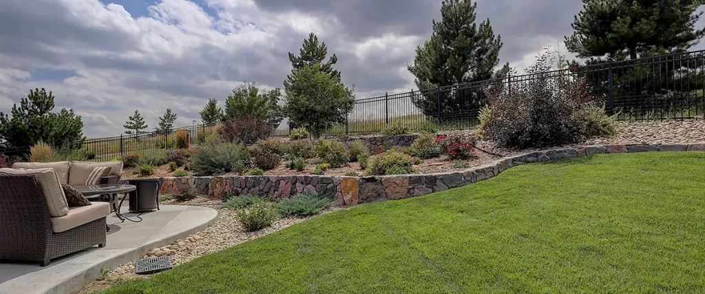 Tiered backyard landscape with stone retaining walls, shrubs, and a seating area in a modern outdoor living space.