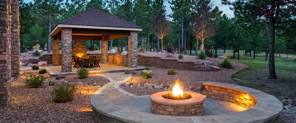 Backyard patio with fire pit and covered seating area surrounded by trees