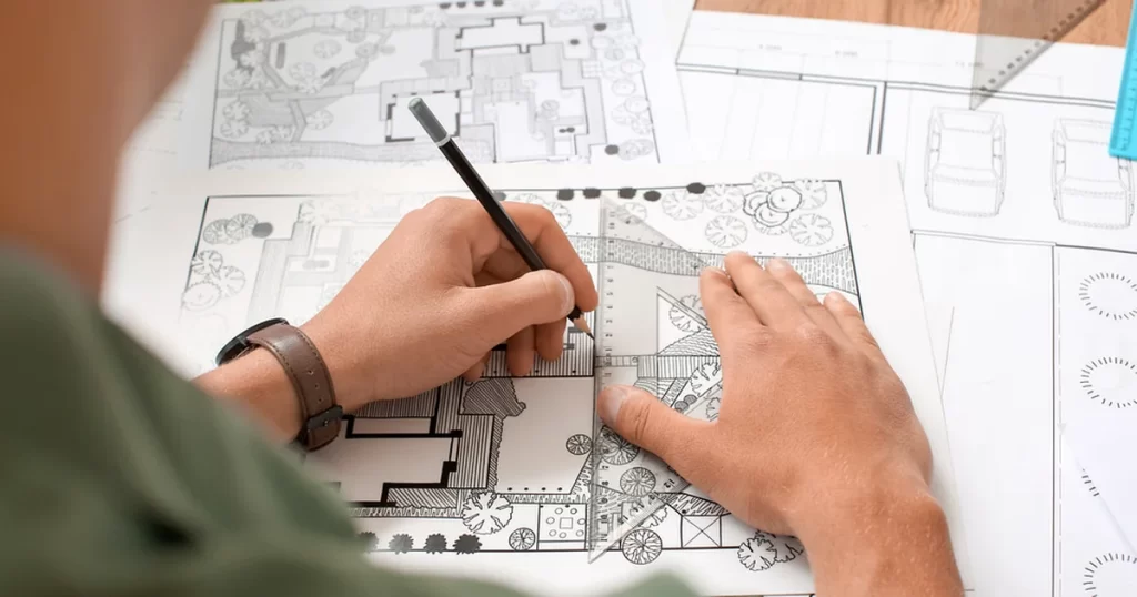 How to design a landscape plan: professional landscape architect drawing a detailed site plan with precision tools.