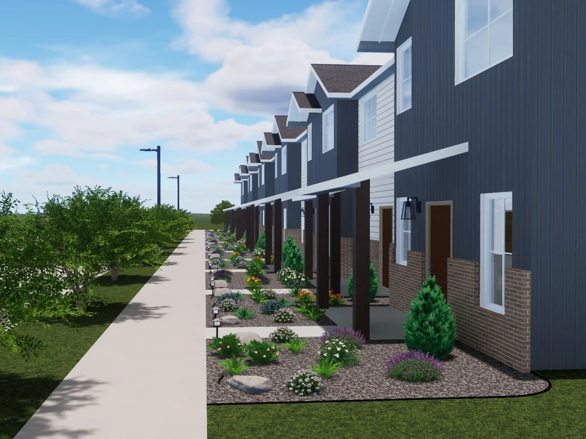 Professional landscape design for a row of modern blue townhomes featuring low-maintenance gravel garden beds, ornamental shrubs, and a concrete sidewalk.